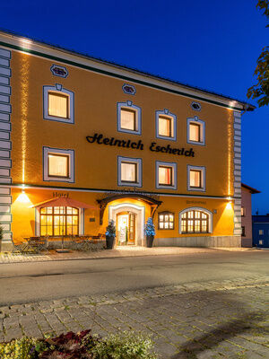 Ein beleuchtetes Gebäude des Hotels Happinger Hof in Rosenheim bei Nachts
